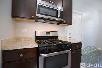 Chicago apartment for rent - A modern kitchen with a stove top oven and microwave above it.