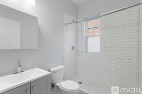 Chicago apartment for rent - A white bathroom with a toilet, sink, and tiled walls.