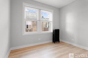Chicago apartment for rent - A room with a window overlooking a brick building and a radiator on the floor.