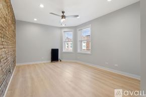 Chicago apartment for rent - A spacious room with a brick wall on the left and a wooden floor.