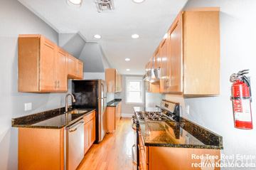 Boston apartment for rent - A kitchen with wooden cabinets and black countertops.