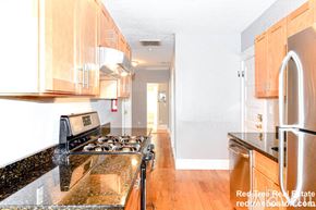 Boston apartment for rent - A kitchen with a black counter top and wooden cabinets.
