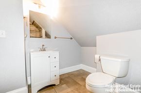 Boston apartment for rent - A white toilet in a small bathroom with a cabinet and a mirror.