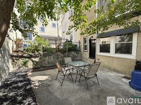 Philadelphia house for rent - A patio with a table and chairs is surrounded by trees.