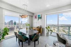 Miami condo for rent - A dining room with a table set for six with a view of the city.