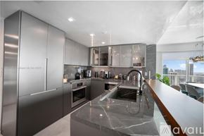 Miami condo for rent - A modern kitchen with stainless steel appliances and a marble countertop.
