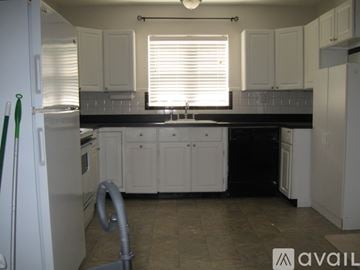 St. Louis house for rent - A kitchen with white cabinets and a black countertop.