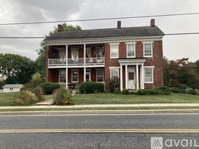 Myersville apartment for rent - A two-story brick house with a porch and a white door.