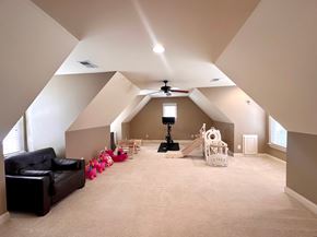 Greer house for rent - A spacious attic room with a ceiling fan and a slide.