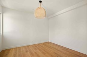 Los Angeles house for rent - A room with a wooden floor and a hanging light fixture.