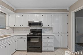 Maumelle house for rent - A kitchen with white cabinets and a black stove top oven.