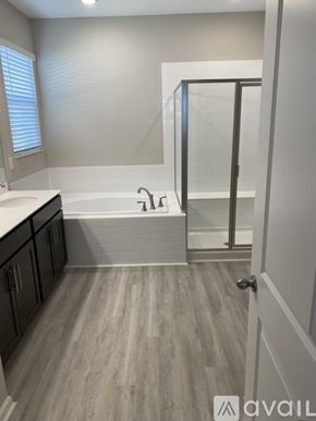 Haines City house for rent - A bathroom with a bathtub, sink, and wooden flooring.