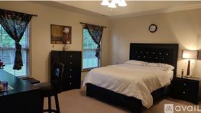 Boiling Springs house for rent - A bedroom with a large bed, a desk, and a window with curtains.