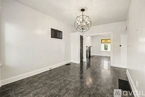 Cincinnati house for rent - A spacious room with a wooden floor and a chandelier hanging from the ceiling.