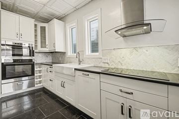 Cincinnati house for rent - A kitchen with white cabinets and a black countertop.