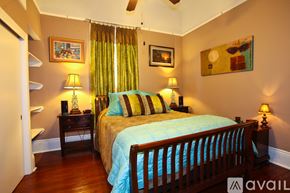 New Orleans house for rent - A bedroom with a bed, two lamps, and a painting on the wall.