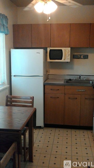 Berea apartment for rent - A kitchen with a white refrigerator, wooden cabinets, and a ceiling fan.