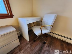 Quincy apartment for rent - A white chair with wheels is placed next to a white desk with drawers.