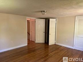 Dedham house for rent - A room with wooden floors and white walls, with a door in the middle and another one to the right.