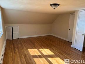 Dedham house for rent - A room with wooden flooring and white walls, with a window on the left and a door on the right.