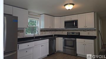 Dedham house for rent - A kitchen with white cabinets and black countertops.