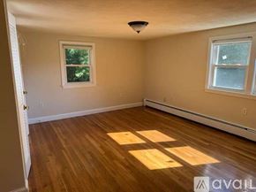 Dedham house for rent - A room with wooden floors and two windows.