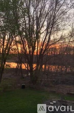 Dedham house for rent - A sunset view with trees and a grassy area.