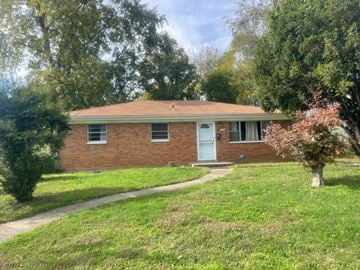 Jeffersonville house for rent - A brick house with a white door and windows surrounded by greenery.