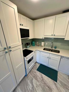 Bradenton house for rent - A kitchen with white cabinets and a black trash can.