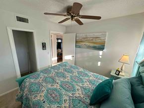 Bradenton house for rent - A bedroom with a bed covered in a patterned bedspread and a ceiling fan.