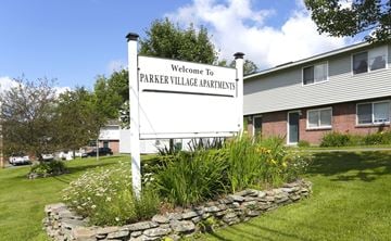 Littleton apartment for rent - A sign that says "Welcome to Parker Village Apartments" stands in front of a building.