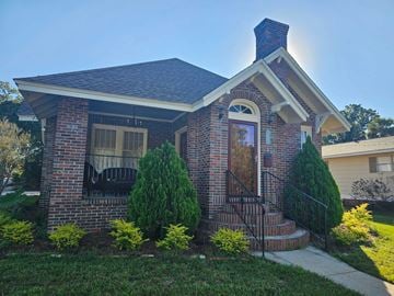 Pensacola house for rent - A small house with a brick facade and a black metal railing.