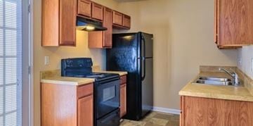 Raeford apartment for rent - A kitchen with black appliances and wooden cabinets.