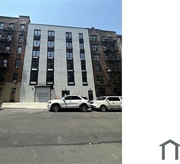Bronx apartment for rent - A white car is parked in front of a tall building.