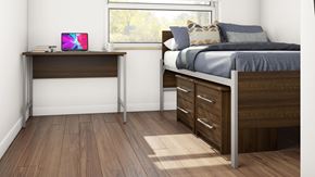 London apartment for rent - A laptop is on a desk in a bedroom with a bed and a window.
