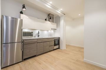Victoria apartment for rent - A modern kitchen with a stainless steel refrigerator and wooden flooring.