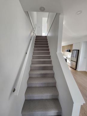 Victoria apartment for rent - A staircase with grey steps leads to a brightly lit room.
