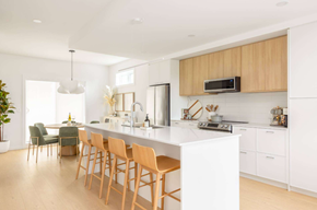 Victoria apartment for rent - A modern kitchen with wooden chairs and white countertops.