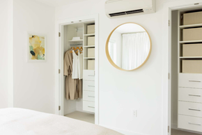 Victoria apartment for rent - A white bedroom with a round mirror and a wardrobe.
