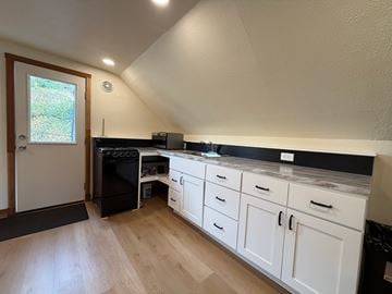 Sitka apartment for rent - A kitchen with white cabinets and a black fridge.