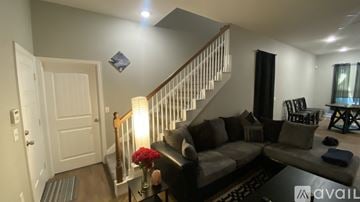 Dallas house for rent - A living room with a grey couch and a staircase.