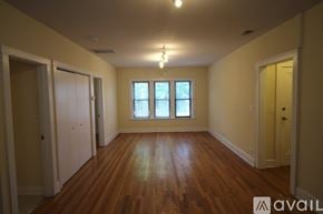 Chicago apartment for rent - A room with wooden floors and a window with white curtains.