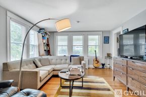 Newton apartment for rent - A living room with a white couch, a coffee table, a guitar, and a television.