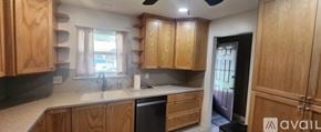 Dade City house for rent - A kitchen with wooden cabinets and a black dishwasher.
