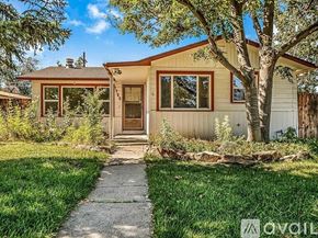 Grand Junction townhouse for rent - A small house with a brown roof and a white door is surrounded by greenery.