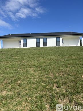 Mount Airy house for rent - A white house with a black roof on a grassy hill.