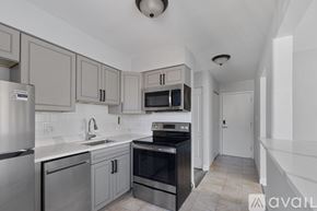 Chicago apartment for rent - A kitchen with a stainless steel refrigerator, a black oven, and a white countertop.