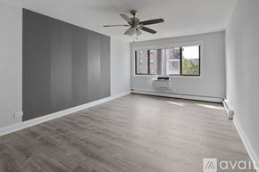 Chicago apartment for rent - A spacious room with a ceiling fan and a window overlooking a cityscape.