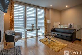 Chicago apartment for rent - A living room with a black couch, a glass coffee table, and a television.