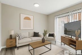 Nashville apartment for rent - A living room with a grey couch, a coffee table, a lamp, a potted plant, and a television.